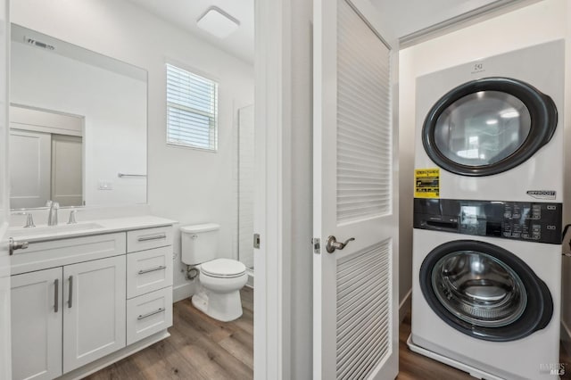 laundry room with visible vents, a sink, stacked washing maching and dryer, laundry area, and dark wood-type flooring