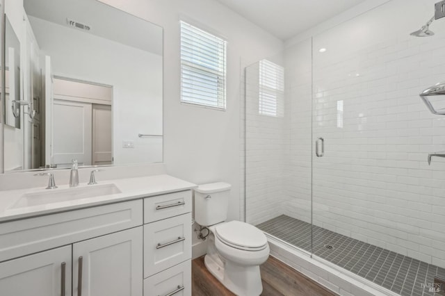 full bathroom featuring toilet, a stall shower, wood finished floors, and visible vents