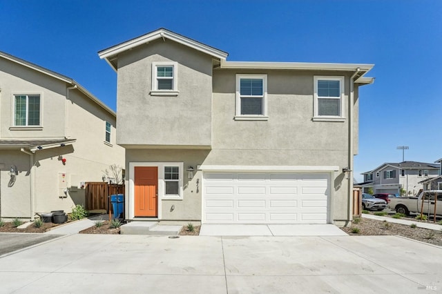 traditional-style house featuring fence, a garage, stucco siding, and driveway