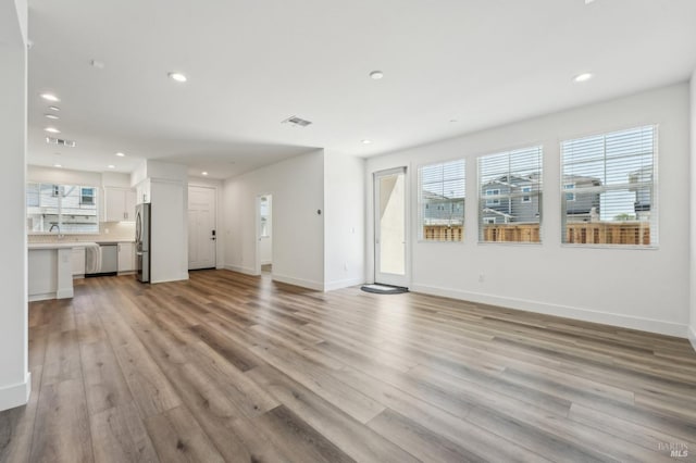 unfurnished living room with light wood-style floors, visible vents, and recessed lighting