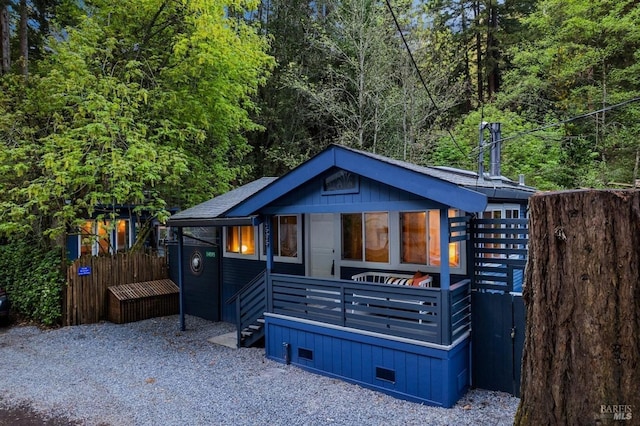 view of front of property with a wooded view, crawl space, fence, and a shingled roof