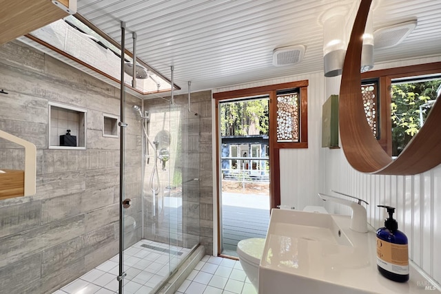 bathroom with a sink, toilet, a shower stall, and tile patterned flooring