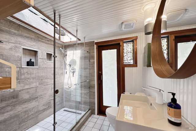 full bathroom featuring a sink, tile patterned flooring, toilet, and a stall shower