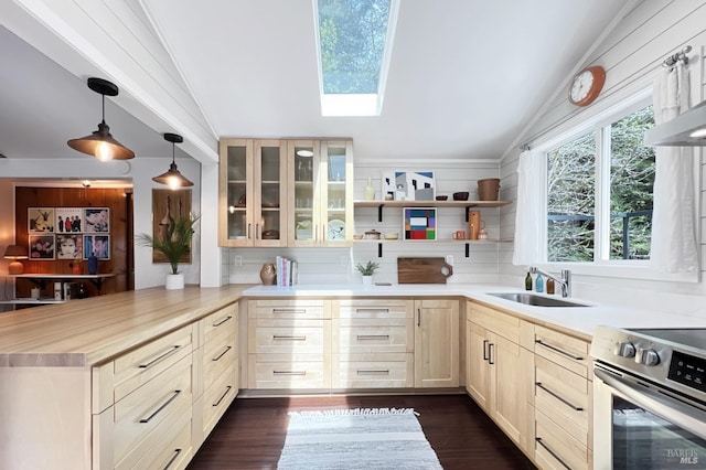 kitchen with dark wood-style flooring, a peninsula, stainless steel range with electric stovetop, lofted ceiling with skylight, and a sink