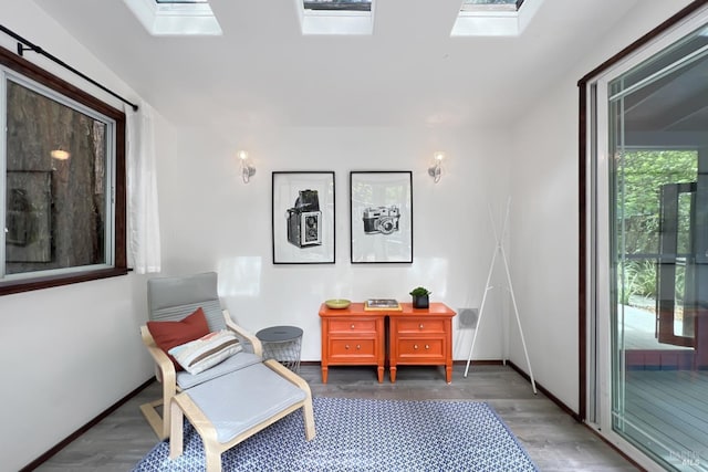 sitting room with baseboards, wood finished floors, and a skylight