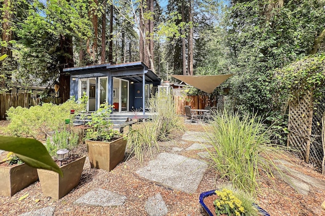 view of yard featuring a patio, a garden, an outdoor structure, and fence