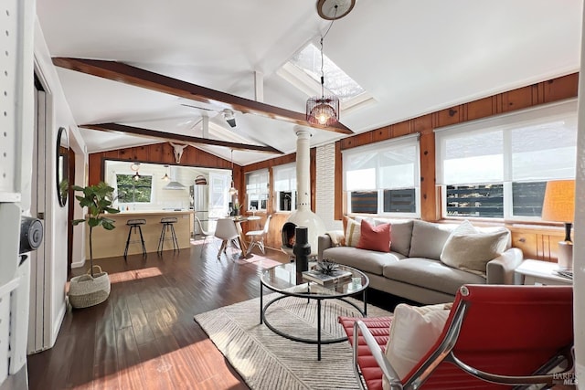 living area with vaulted ceiling with skylight, dark wood-style flooring, and ceiling fan