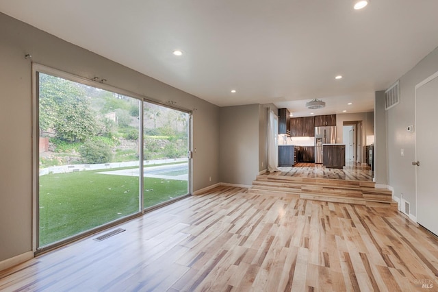 unfurnished living room featuring light wood finished floors, baseboards, visible vents, and recessed lighting