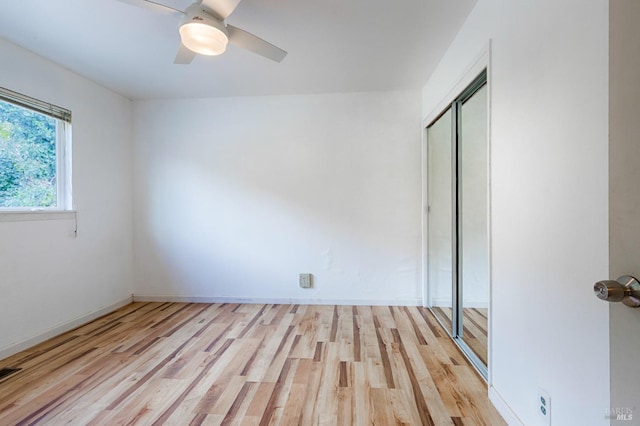 unfurnished bedroom featuring a closet, light wood-type flooring, baseboards, and ceiling fan