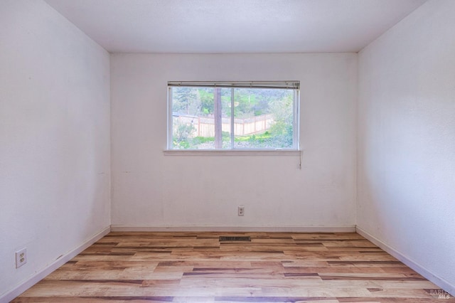 unfurnished room with visible vents, light wood-style flooring, and baseboards