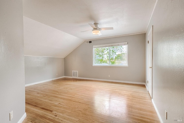 additional living space featuring light wood finished floors, visible vents, vaulted ceiling, and a ceiling fan