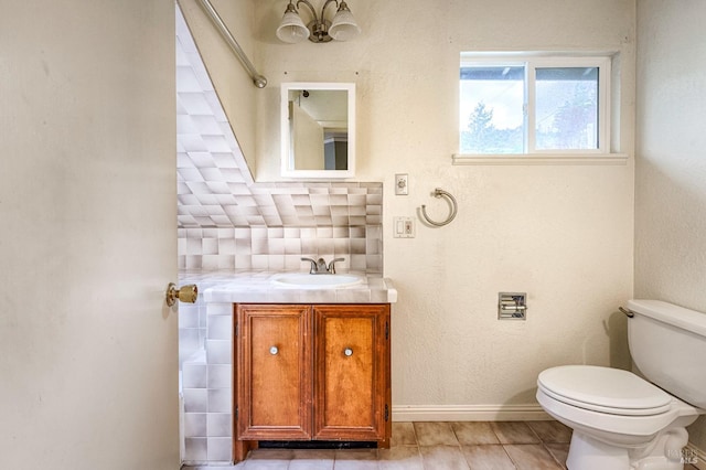 bathroom featuring vanity, tile patterned flooring, toilet, decorative backsplash, and baseboards