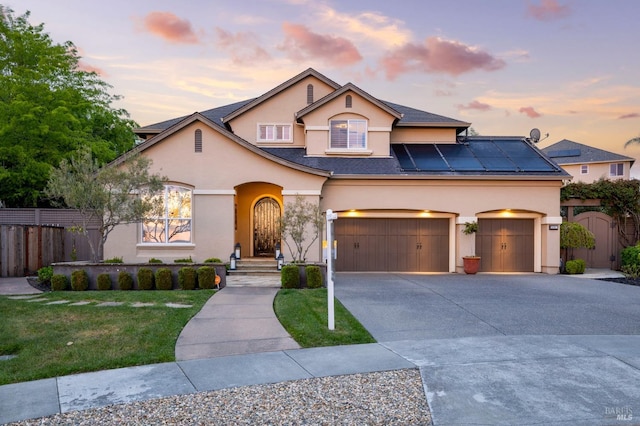 view of front of property with stucco siding, fence, solar panels, a gate, and driveway