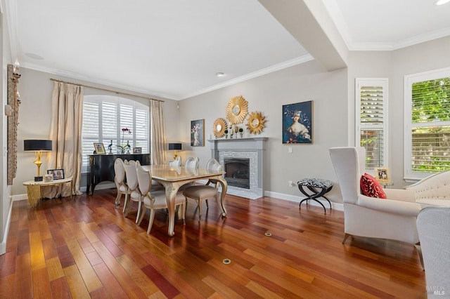 dining space featuring a fireplace with flush hearth, hardwood / wood-style flooring, and crown molding