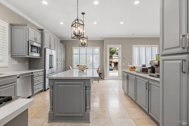 kitchen featuring ornamental molding, light countertops, appliances with stainless steel finishes, and gray cabinetry
