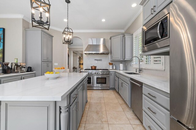 kitchen with a sink, wall chimney exhaust hood, appliances with stainless steel finishes, and gray cabinets
