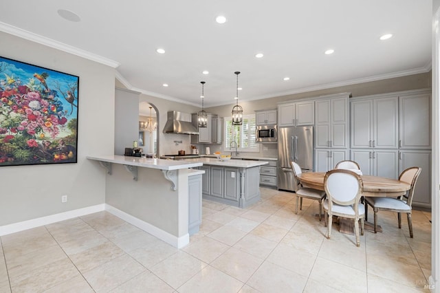 kitchen with wall chimney exhaust hood, appliances with stainless steel finishes, light countertops, a breakfast bar area, and gray cabinetry