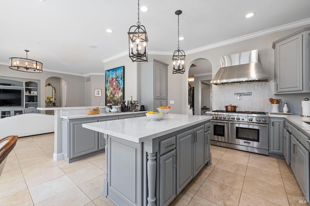 kitchen featuring wall chimney range hood, gray cabinetry, and double oven range