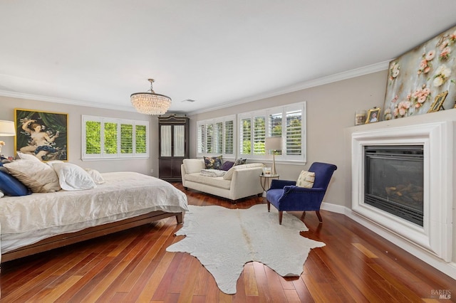 bedroom with wood-type flooring, ornamental molding, a glass covered fireplace, and a notable chandelier