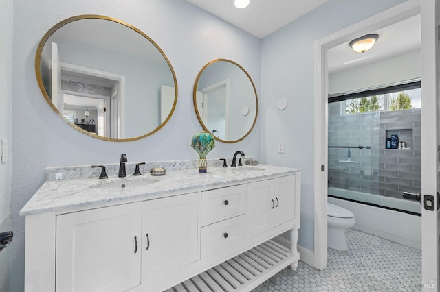 bathroom with double vanity, a sink, toilet, and enclosed tub / shower combo