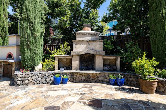 view of patio / terrace with a fenced backyard and an outdoor stone fireplace