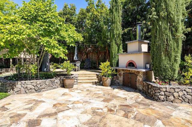 view of patio / terrace featuring exterior fireplace and fence