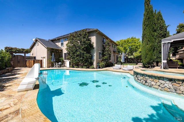pool featuring a patio area, an in ground hot tub, and fence
