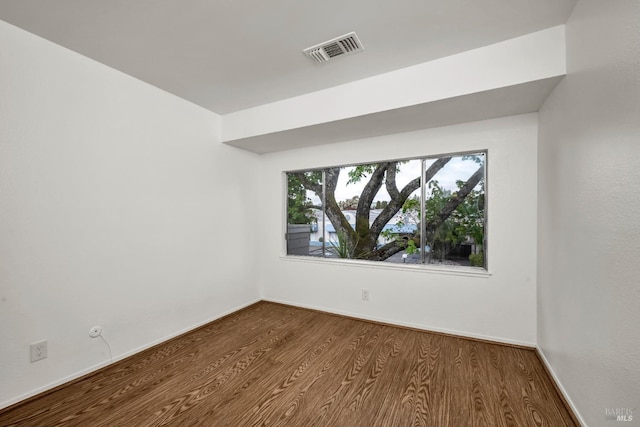 spare room with baseboards, dark wood finished floors, and visible vents