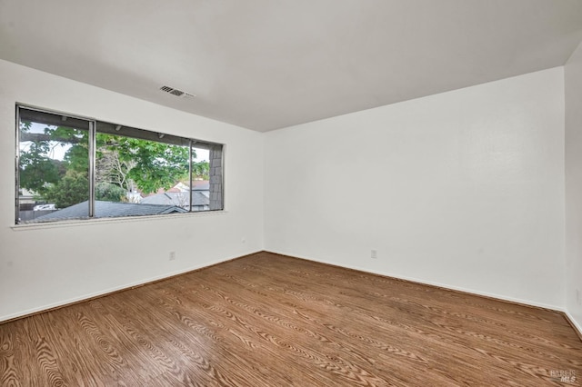unfurnished room featuring visible vents, baseboards, and wood finished floors