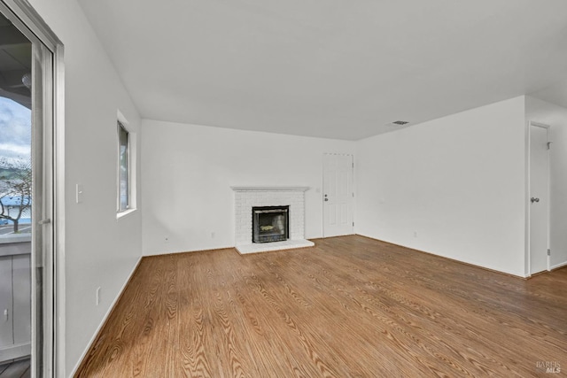 unfurnished living room with wood finished floors, a fireplace, and visible vents