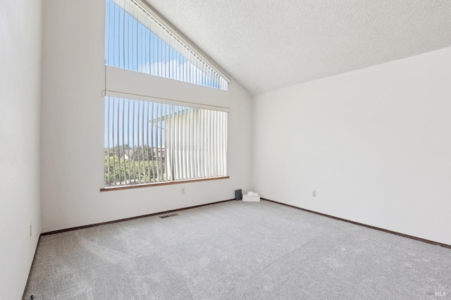 empty room featuring carpet flooring, a textured ceiling, visible vents, and baseboards