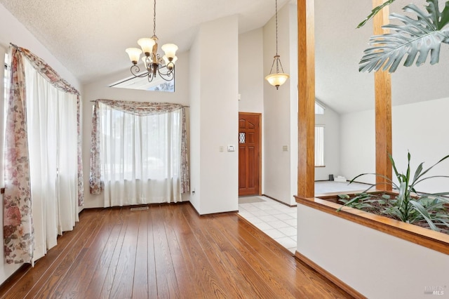 interior space featuring visible vents, high vaulted ceiling, a chandelier, and hardwood / wood-style flooring