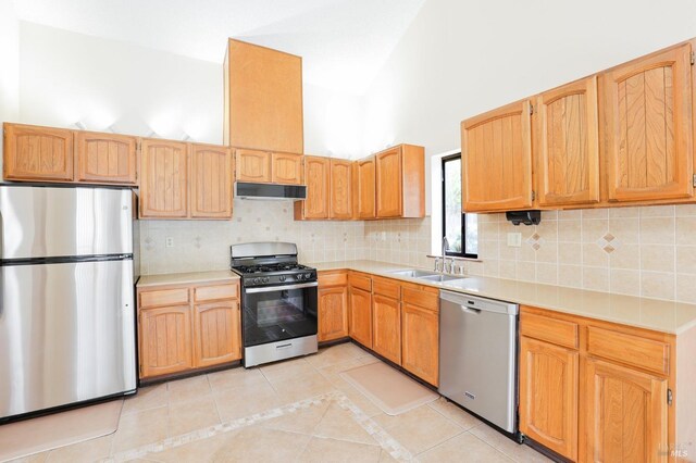 kitchen with decorative backsplash, light countertops, under cabinet range hood, a sink, and stainless steel appliances