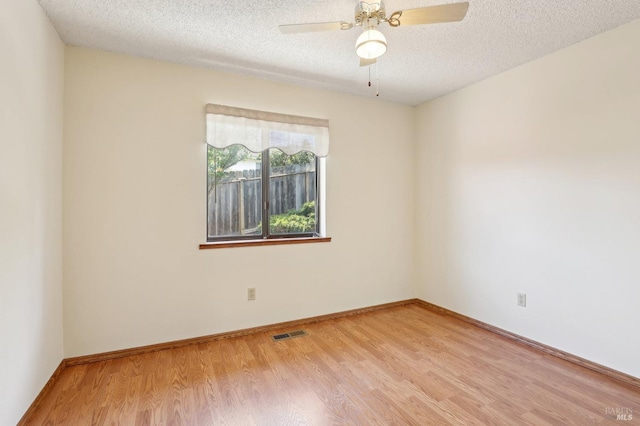unfurnished room with ceiling fan, a textured ceiling, visible vents, baseboards, and light wood finished floors