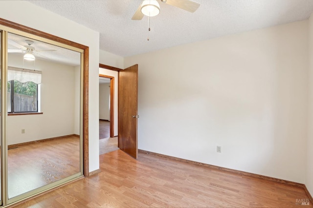 unfurnished bedroom with a closet, light wood-style floors, baseboards, ceiling fan, and a textured ceiling