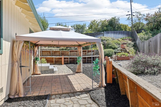 view of patio featuring a fenced backyard, a gazebo, and a garden
