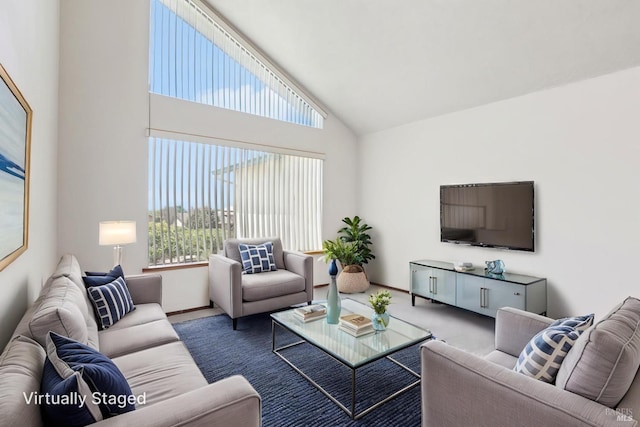 carpeted living room with high vaulted ceiling and baseboards