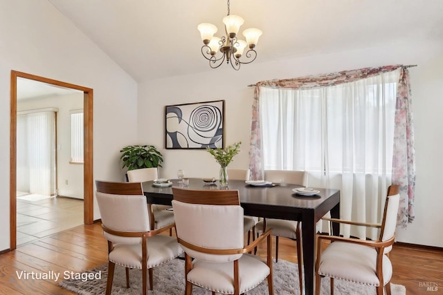 dining space featuring a chandelier, plenty of natural light, wood finished floors, and vaulted ceiling