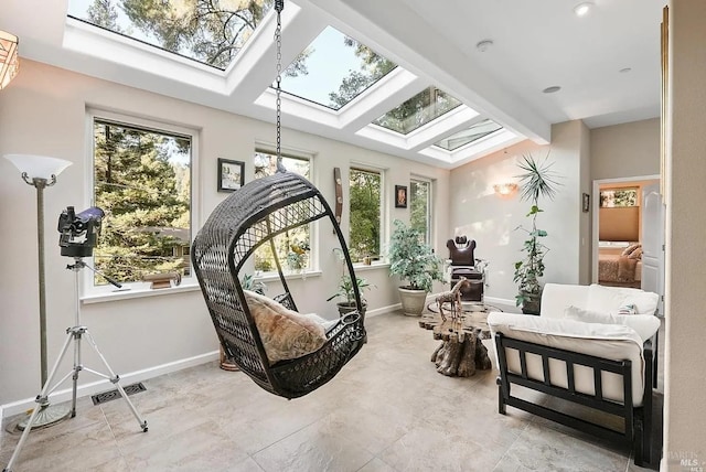 living area featuring vaulted ceiling with skylight, visible vents, and baseboards