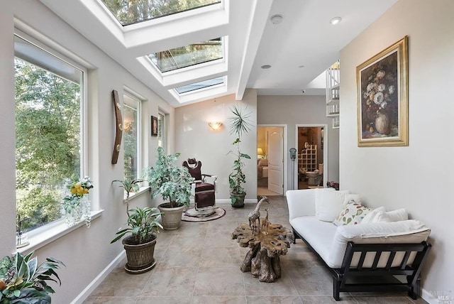 living area featuring vaulted ceiling with skylight and baseboards