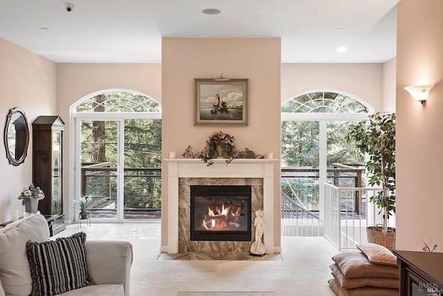 carpeted living area featuring a tiled fireplace and a healthy amount of sunlight