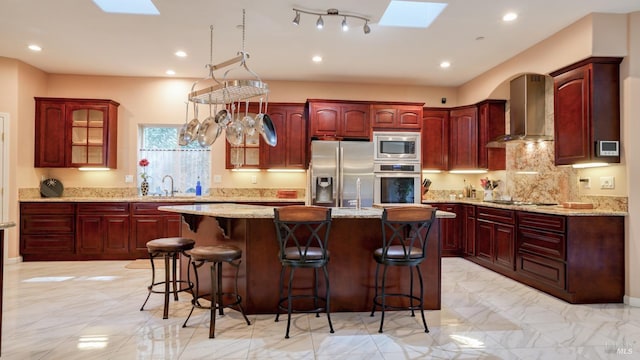 kitchen with wall chimney exhaust hood, dark brown cabinets, and stainless steel appliances