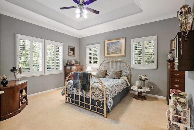 bedroom with carpet, a tray ceiling, baseboards, and a ceiling fan