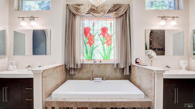 full bath featuring a bath, a wealth of natural light, two vanities, and a sink