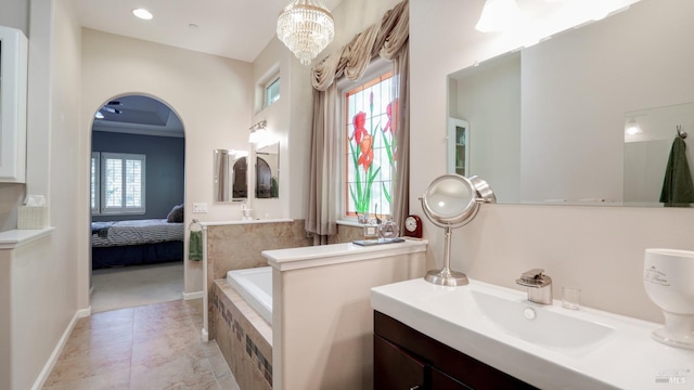 bathroom with ensuite bathroom, a bath, an inviting chandelier, and vanity