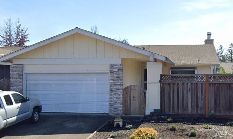 ranch-style house featuring a garage, a chimney, aphalt driveway, brick siding, and fence