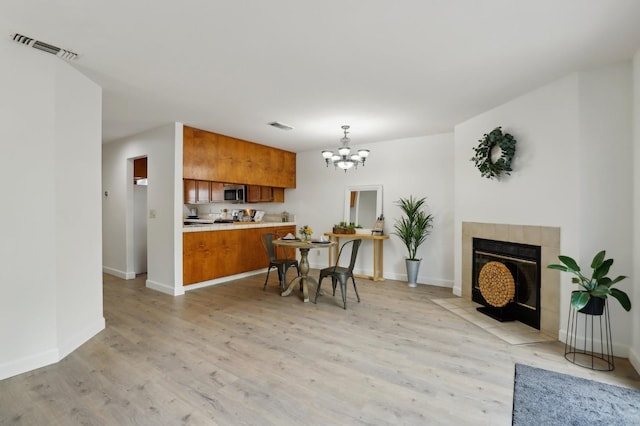 interior space featuring brown cabinetry, a chandelier, light wood finished floors, light countertops, and stainless steel microwave