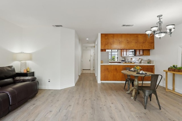 kitchen featuring brown cabinetry, baseboards, open floor plan, and tile countertops