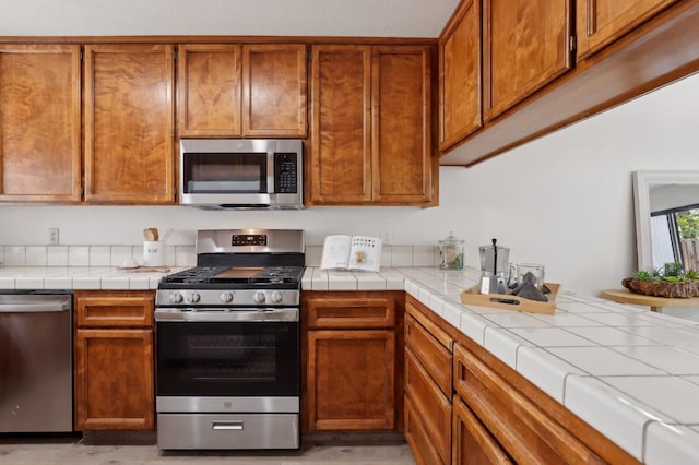 kitchen with brown cabinetry, stainless steel appliances, and light wood-style flooring