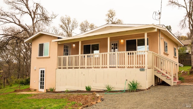 view of front of house featuring stairway, covered porch, and stucco siding
